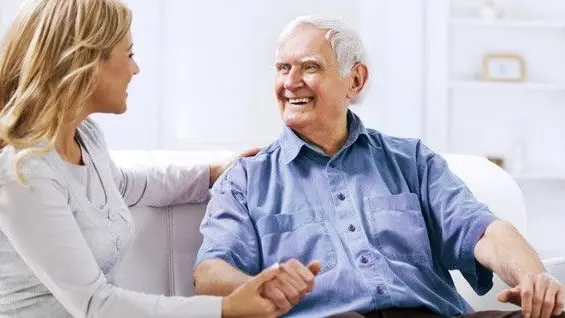 An older man holding hands with a younger woman at home